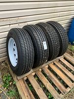 Four tires on rims on pallet, side view