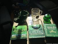 Group shot showing all six items: three CD tins, glass stein, ceramic boot mug, lidded jar