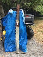 Full view of long crosscut saw leaning against tarp-covered object