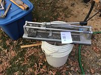 Manual tile cutter full view on bucket outdoors