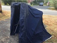 Angle view of assembled blue portable ice fishing shelter showing overall form and fabric wear