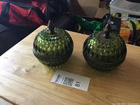 Two green diamond point lidded candy dishes on table
