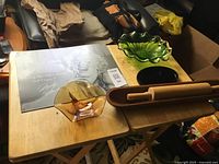 Overview of lot on table showing rolling pin in holder, Marilyn Monroe tin sign, green ruffled bowl, black dish, amber bowl with copper spoons