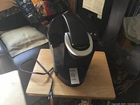 Front view of Keurig coffee maker on table showing power cord and water reservoir