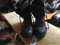 Front view of both Kamik boots showing brown uppers and black rubber lowers