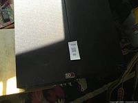 Front view of one speaker showing grille and badge