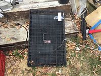 Top view of folded black wire dog crate on ground