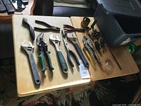 Hand tools laid out including adjustable wrenches, snips, pliers, wire brush and bin