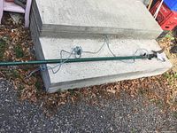 Full view of green extending pole pruner lying on ground