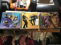 Stack of LPs on table; three album covers visible