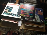 Two stacks of vinyl LP albums on folding tables, top covers visible