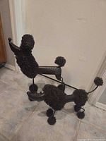 Both metal poodle sculptures standing on tile floor
