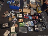 Overview of several boxes and loose piles of Magic: The Gathering cards on surface