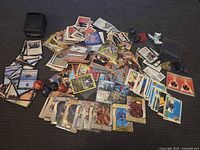 Pile of mixed trading cards, Bakugan balls and figures spread on carpet