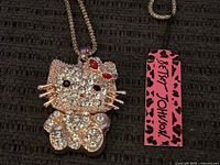 Close-up of pendant and tag showing rhinestones, enamel bow, Betsey Johnson branding