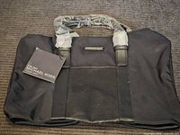 Front view of Michael Kors men’s bag lying flat