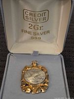 Pendant in presentation box showing coin and mount