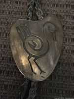 Close-up of sterling silver bolo slide showing stylized bird design and tarnish level