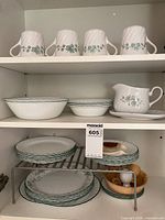 Overview of mugs, bowls, creamer, plates and egg cups in cabinet
