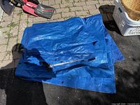 Stack of folded blue tarps showing surface and grommets