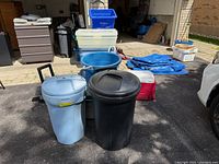 Front view showing two round garbage cans, blue tub, stack of clear storage totes, blue recycling bin, and Igloo cooler