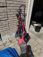 Group view of shovels, hand truck and snow brush leaning against wall