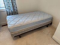Twin mattress on box spring and metal frame, full view from side