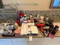 Countertop view of toiletries, hair dryers, curling iron, wire rack, decorative jars
