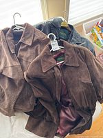 Three coats displayed: two brown suede, one black leather
