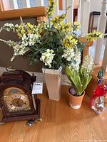 Group shot showing mantel clock, tall vase with flowers, terracotta pot with flowers, glass parrot figurine