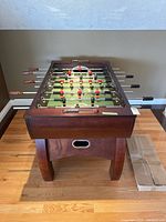 Full view of wooden foosball table on hardwood floor