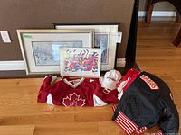 Group shot of jersey, jacket, cap, three prints