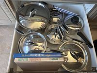 Drawer containing Lagostina pots, extra pot, steamer basket and cookbooks