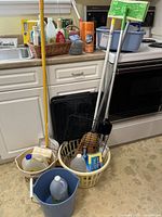 Overall view of cleaning tools, buckets, baskets, jugs, broom, Swiffer, grill grids