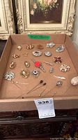 Overview of entire lot showing brooches and hat pins in cardboard tray