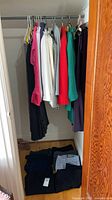 Closet view of hanging tops/blazers and folded pants
