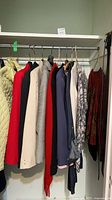Assorted blazers, jackets and sweaters hanging on closet rod