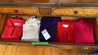 Drawer showing six folded sweaters of various colours