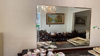 Full view of large frameless mirror mounted horizontally over sideboard