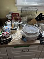 Countertop view with casserole dishes, utensil block, wire rack, timer and assorted utensils