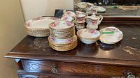 Stacked dinner and bread plates, dessert bowls, cups, saucers, cream and sugar on dresser
