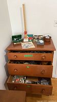 Full view of dresser drawers open showing sewing notions and items on top