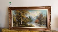 Framed landscape painting hung on wall showing full artwork and frame