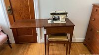 Singer sewing machine on cabinet with bench