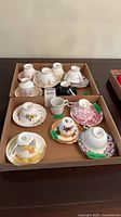 Tray with eleven teacup-saucer sets and one mug
