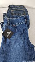 Pair of folded jeans showing Jordache hangtag and back pocket stitching