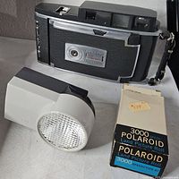 Polaroid 900 Electric Eye camera beside box of 3000 speed film and Wink-Light flash