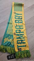 Full view of signed green and yellow Tampa Bay Rowdies scarf with tag