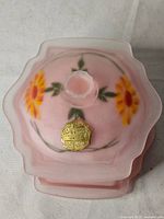 Top view of pink frosted glass powder jar showing floral motif and scalloped lid