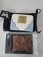 Both wallets: cream/light blue snap wallet and boxed brown bifold wallet